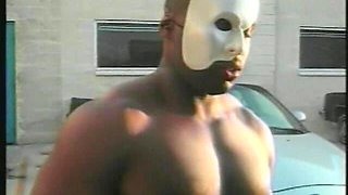 Muscular Stranger in White Superhero Mask Drills Ebony Chick on the Parking of Shopping Mall