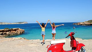 Two beautiful girls have fun on the beach with a guy, showcasing sensual moves.